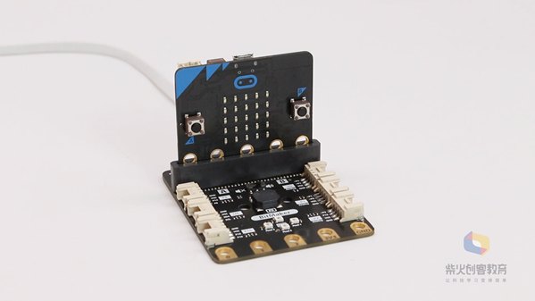 Carte micro:bit insérée debout dans un shield BitMaker, avec son câble USB branché.